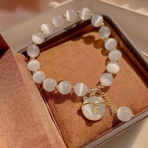 Elegant white cat's eye bead bracelet with golden cat pendant in a luxury jewelry box