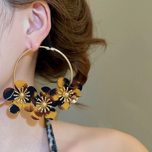 Close-up of gold hoop earrings with leopard print fabric flowers on a female model