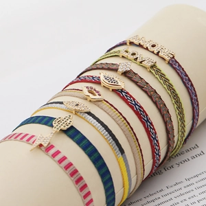 Macro detail of Bohemian woven bracelets with gold charms and sparkling crystal accents