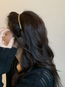 Nahaufnahme eines minimalistischen mehrreihigen Goldhaarreifens mit Textur auf Wellenhaar