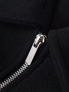 Detailed macro view of high-quality silver metal zipper on black wool blend fabric