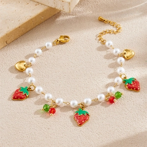 Sweet pearl bracelet with strawberry pendant and heart charm on natural stone background