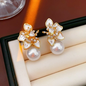 Macro shot of gold floral earrings featuring white pearls and heart-shaped zircon stones