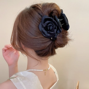 Dettaglio di elegante molletta per capelli a rosa in raso nero su acconciatura donna
