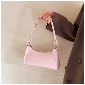 Close-up of pink baguette bag with glossy finish and elegant knotted strap detail