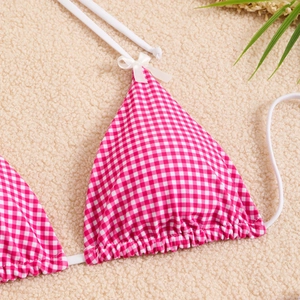 Detail shot of pink gingham bikini top with white bows and halter neck straps