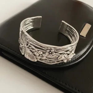 Vintage silver open bangle with embossed butterfly and floral patterns on black leather