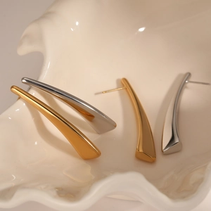 Minimalist long geometric arc earrings in gold and silver finish on a shell tray