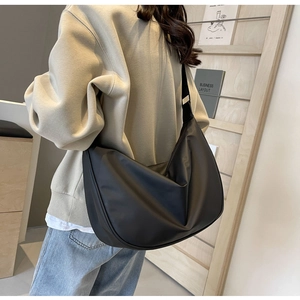Macro view of minimalist black crossbody dumpling bag with metal buckle detail