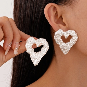 Elegant silver heart earrings with textured liquid metal design shown on ear model
