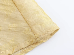 Gros plan sur la texture du tissu jacquard doré aux motifs floraux élégants sur la robe