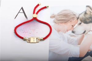 Detail of red braided cord bracelet with gold cross padlock and inlaid zircon crystals