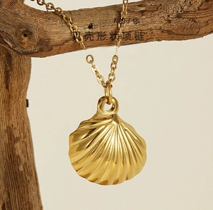 Detailed view of a golden shell pendant necklace hanging on a natural wooden branch