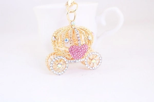 Gros plan d'un porte-clés carrosse citrouille doré avec détail de cœur en strass rose