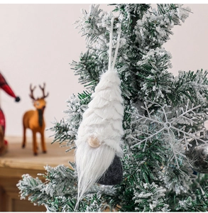 Detail of a Nordic Christmas gnome hanging on a snowy tree with long white fur texture