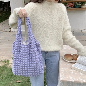 Detail view of purple popcorn texture fabric on a stylish tote bag held by a model