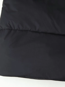Detailed macro view of black quilted fabric with precise stitching on winter coat