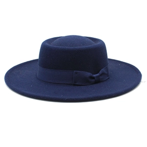Detail of the navy blue wide-brimmed felt fedora hat featuring a matching ribbon bow