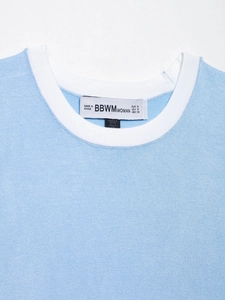 Gros plan d'un haut en tricot bleu clair avec col rond contrasté blanc et étiquette