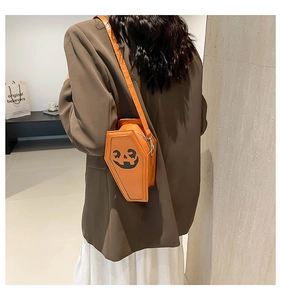 Ghost-themed coffin shaped orange crossbody bag with pumpkin face print worn by a model