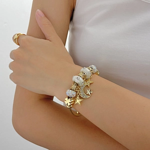 Gold star and moon charm wire bracelet and minimalist ring worn by a fashion model