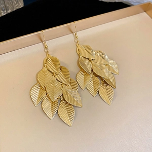 Detail shot of golden leaf tassel earrings with textured layers on a display tray