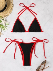 Flat lay of textured black and red bikini set with summer beach accessories