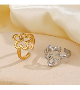 Detailed macro shot of gold and silver cutout flower rings on a soft silk background