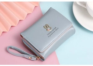 Nahaufnahme der graublauen Lederbrieftasche mit Kaninchen-Metalllogo und Blumenmustern