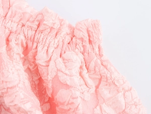 Dettaglio del tessuto jacquard rosa goffrato con bordi a pieghe elasticizzati
