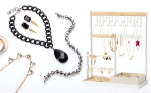 Detail of white double-tier jewelry organizer with necklaces on wooden bar and tray