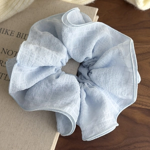 Close-up of light blue pleated oversized scrunchie on a book with soft lighting