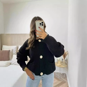 Gilet noir pour femme en maille épaisse avec boutons dorés et manches bouffantes élégantes