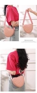 Detail of pink heart-shaped crossbody bag with V-quilt stitching and leather strap
