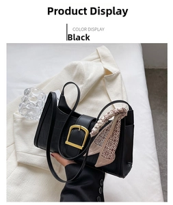 Close-up of black crocodile-textured shoulder bag with gold square buckle and decorative scarf