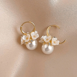 Close-up of golden floral hoop earring with pearls and rhinestones on silk