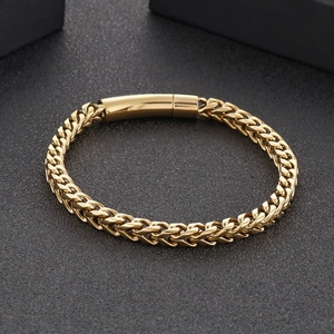 Detalle de pulsera dorada para hombre con cadena de trigo y cierre cilíndrico seguro