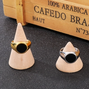 Polished stainless steel signet rings with black circular inlay on wooden cone stands