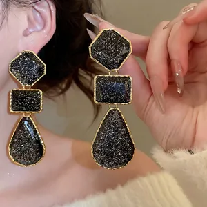 Exaggerated geometric drop earrings with black glitter resin and gold metal borders