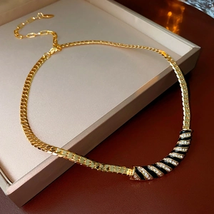 Dettaglio della collana vintage placcata oro con smalto nero e cristalli su scatola beige