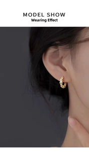 Detailed view of a model wearing a textured golden s999 silver C-shaped hoop earring