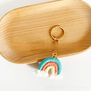 Detailed view of handmade woven rainbow keychain with white tassels and gold metal ring