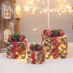 Three rattan Christmas gift boxes with LED lights and pine cone accents on faux snow