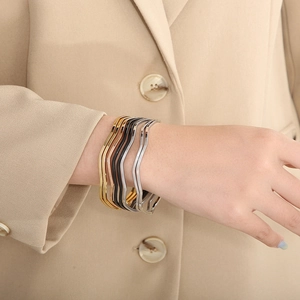 Nahaufnahme der gedrehten Armreifen in Gold, Silber, Roségold und Schwarz am Handgelenk