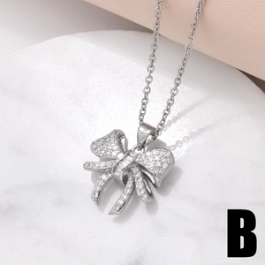 Elegant silver bow pendant necklace with cubic zirconia on white marble and silk