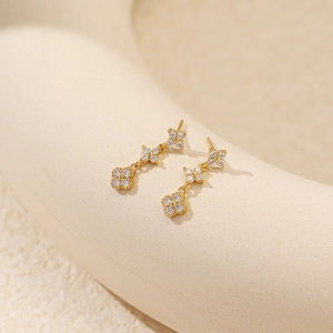 Macro view of gold-plated triple clover earrings with shimmering cubic zirconia stones
