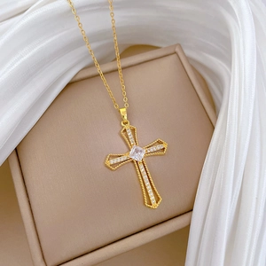 Detailed view of a gold hollow cross pendant with sparkling crystals and fine chain