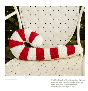 Detail of red and white candy cane shaped Christmas pillow on a white chair