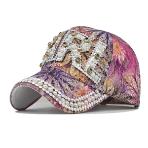 Detailed view of the sparkling rhinestone R letter and pearl trim on a floral baseball cap