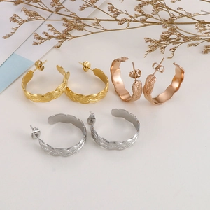 Macro detail of C-shaped hoop earrings featuring vintage twisted braided metal texture